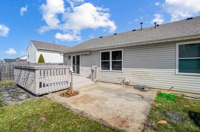 rear view of property with a patio, roof with shingles, a deck, and fence