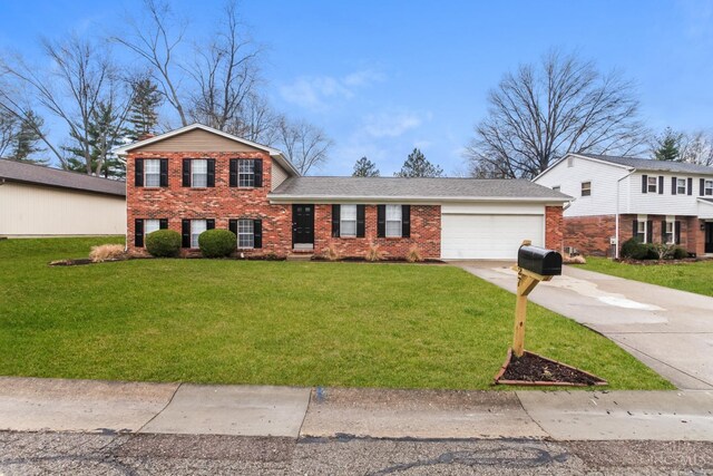 split level home with a front yard, a garage, brick siding, and driveway
