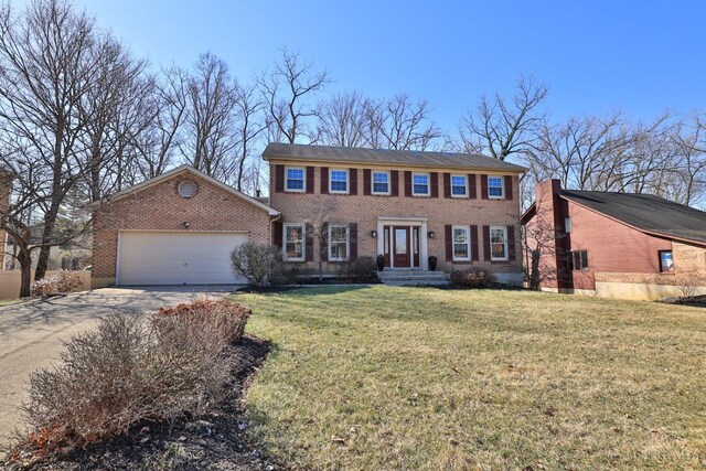 colonial home featuring brick siding, driveway, an attached garage, and a front yard