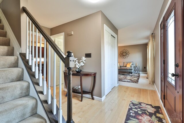 entrance foyer with stairway, baseboards, and light wood finished floors