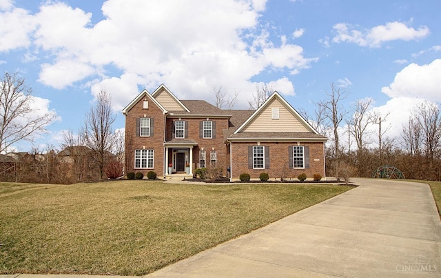 view of front of house featuring a front yard, brick siding, and driveway