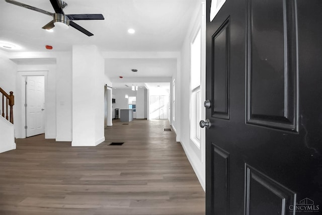 entryway featuring visible vents, a ceiling fan, wood finished floors, stairway, and baseboards