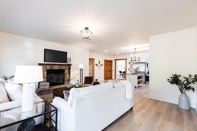 6114 Reily Millville Rd, Reily Twp, OH 45056 - living room with a notable chandelier, baseboards, light wood-style floors, and a stone fireplace