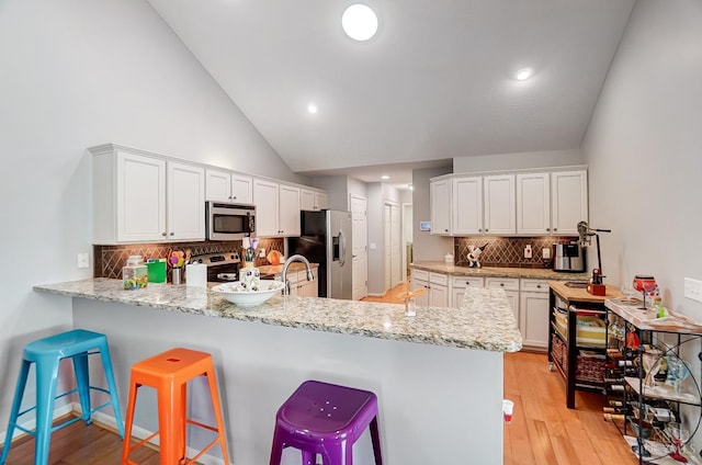 kitchen featuring white cabinetry, a peninsula, light wood-style flooring, and appliances with stainless steel finishes