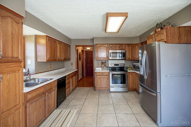 343 Whiteoak Dr, Wilmington, OH 45177 - kitchen with appliances with stainless steel finishes, a sink, light countertops, brown cabinets, and light tile patterned flooring