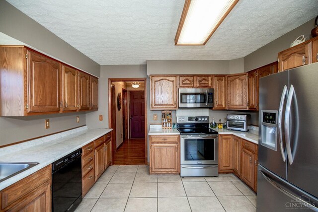343 Whiteoak Dr, Wilmington, OH 45177 - kitchen featuring appliances with stainless steel finishes, light countertops, brown cabinetry, and a textured ceiling
