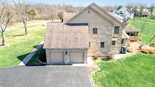 343 Whiteoak Dr, Wilmington, OH 45177 - view of property exterior featuring central AC, asphalt driveway, brick siding, and a lawn