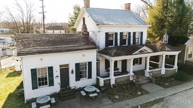 view of front of property with brick siding, covered porch, and a chimney