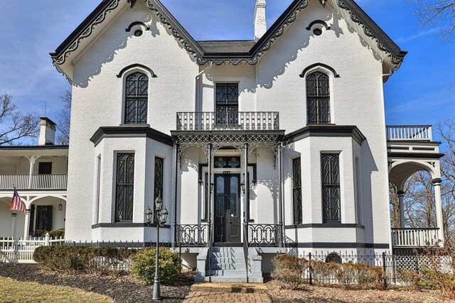 view of front of house featuring a balcony and brick siding