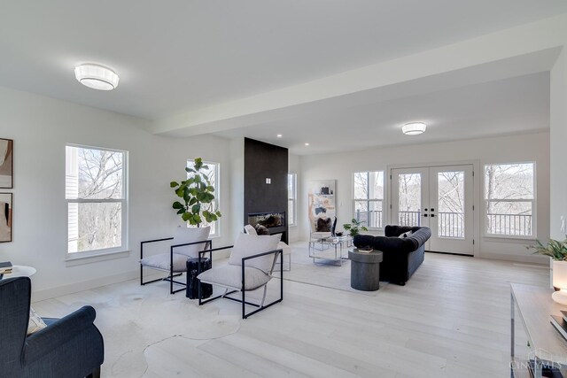 living room featuring french doors, light wood-type flooring, baseboards, and a multi sided fireplace