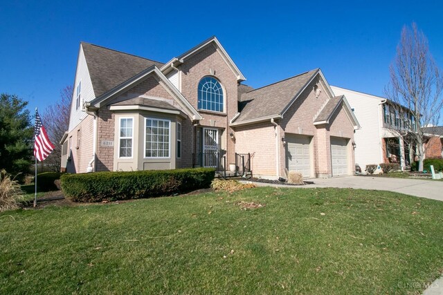 view of front facade featuring an attached garage, driveway, a front lawn, brick siding, and a shingled roof