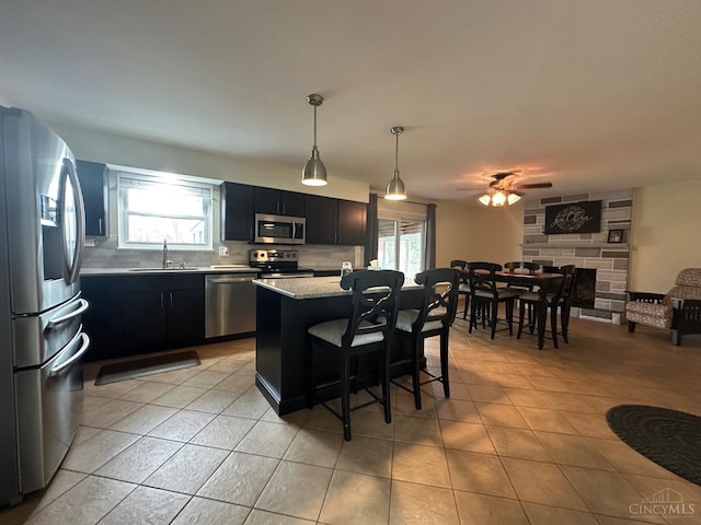 kitchen featuring a sink, stainless steel appliances, decorative backsplash, light tile patterned floors, and dark cabinetry