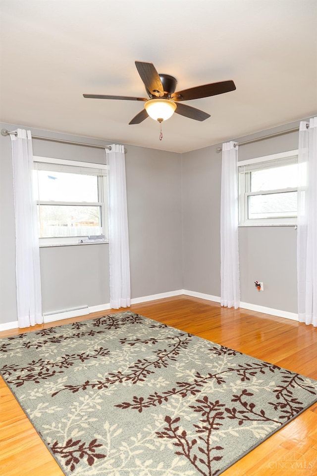 spare room with a ceiling fan, baseboards, and wood finished floors
