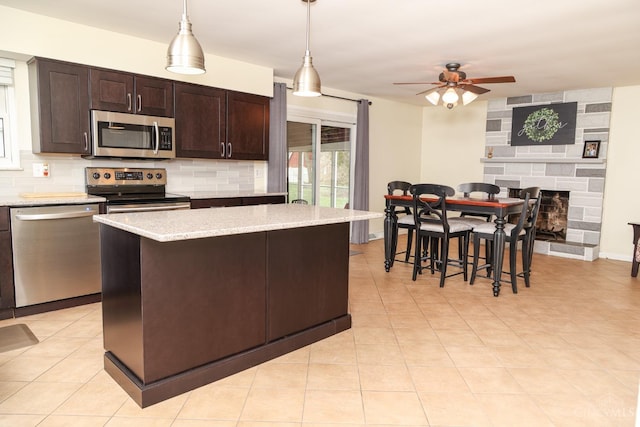 kitchen with ceiling fan, dark brown cabinetry, backsplash, a fireplace, and appliances with stainless steel finishes