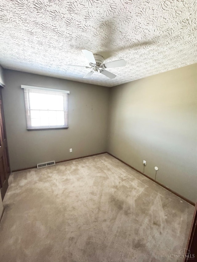 unfurnished room featuring a ceiling fan, a textured ceiling, visible vents, and carpet floors