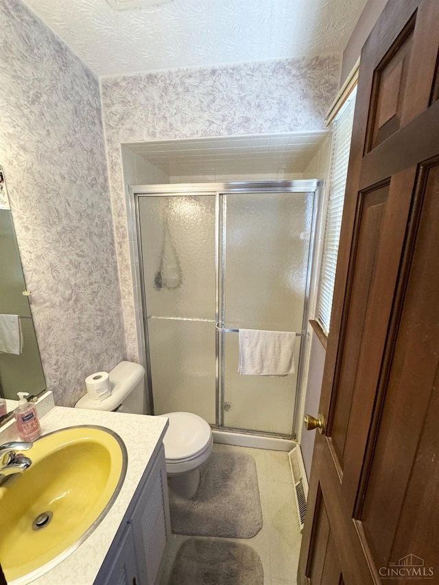 bathroom featuring vanity, toilet, a shower stall, and wallpapered walls