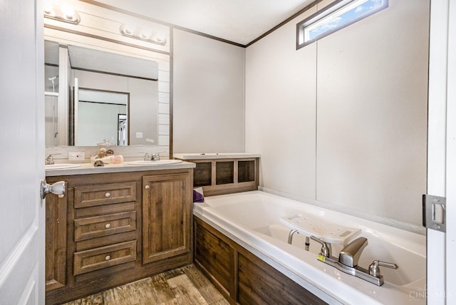 full bathroom with double vanity, a bath, and wood finished floors