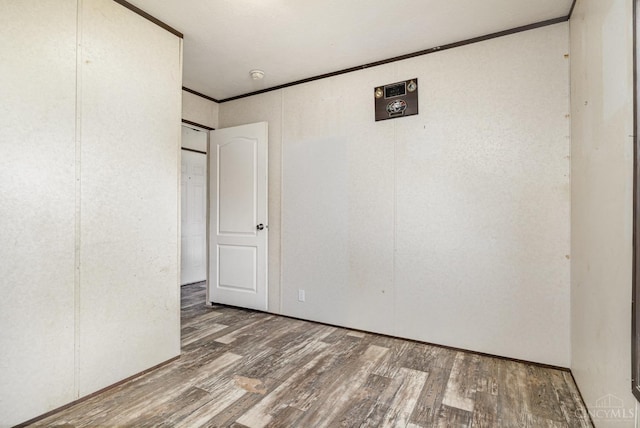 spare room featuring wood finished floors, crown molding, and a smoke detector