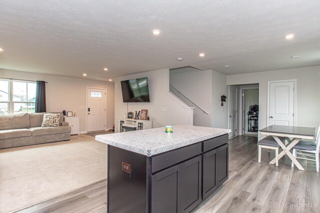 kitchen featuring light countertops, a kitchen island, open floor plan, light wood-style floors, and recessed lighting