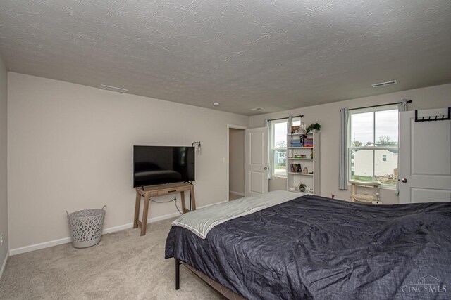 carpeted bedroom with a textured ceiling, baseboards, and visible vents