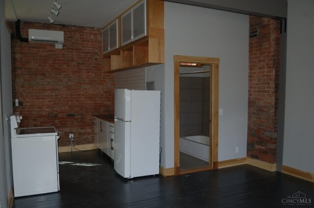 kitchen featuring dark wood-style flooring, an AC wall unit, brick wall, freestanding refrigerator, and range with electric stovetop