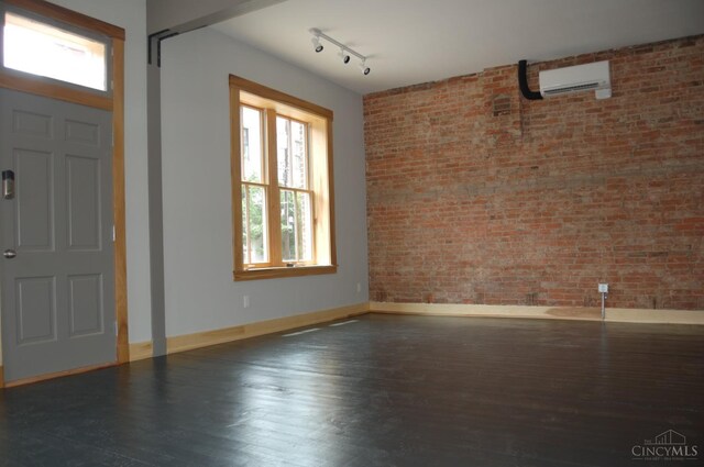 foyer featuring track lighting, wood finished floors, brick wall, a wall mounted air conditioner, and baseboards