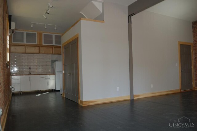 interior space featuring baseboards, tasteful backsplash, freestanding refrigerator, and a sink