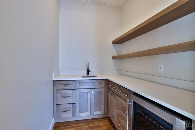 bar featuring a sink, wine cooler, wood finished floors, and ornamental molding