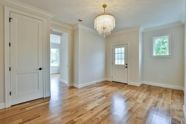 entryway with a chandelier, ornamental molding, baseboards, and light wood-type flooring