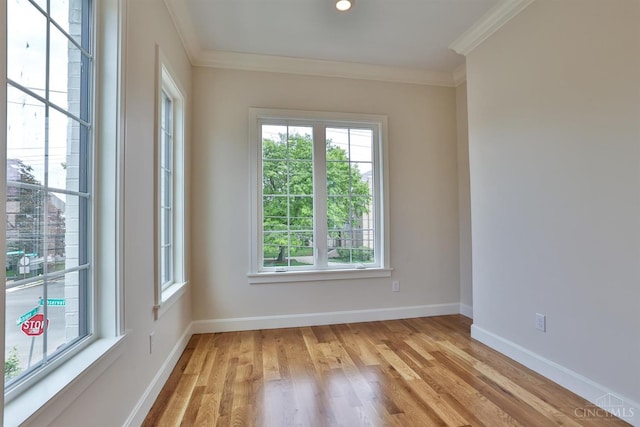unfurnished room featuring plenty of natural light, ornamental molding, light wood finished floors, and baseboards