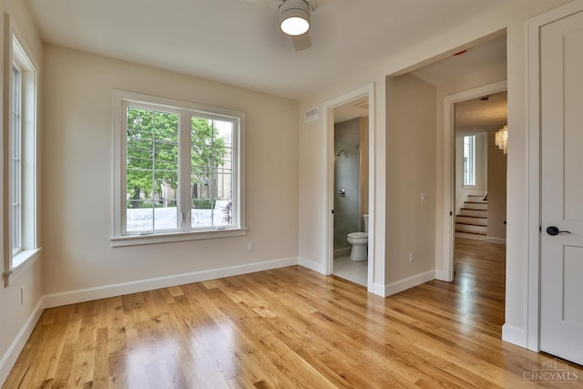 empty room featuring healthy amount of natural light, light wood-type flooring, baseboards, and a ceiling fan