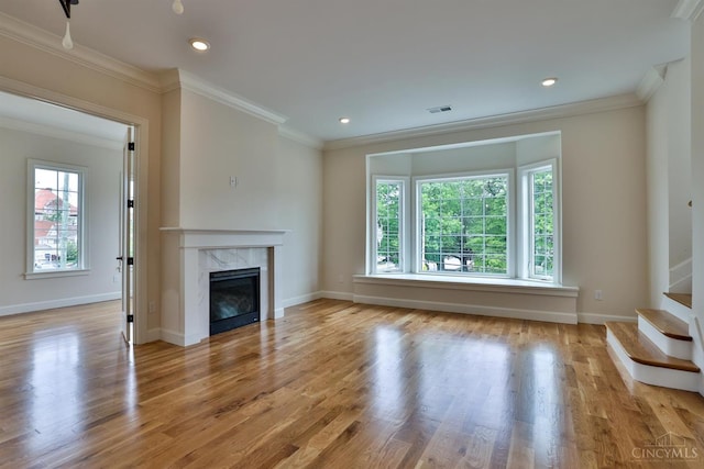 unfurnished living room featuring crown molding, stairway, a premium fireplace, wood finished floors, and baseboards