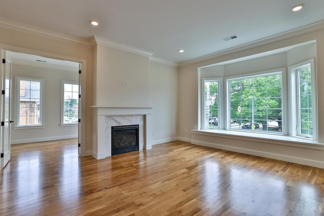 unfurnished living room with ornamental molding, wood finished floors, a high end fireplace, baseboards, and recessed lighting