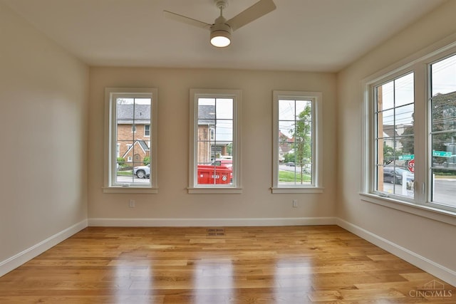 empty room featuring a ceiling fan, light wood-type flooring, and baseboards