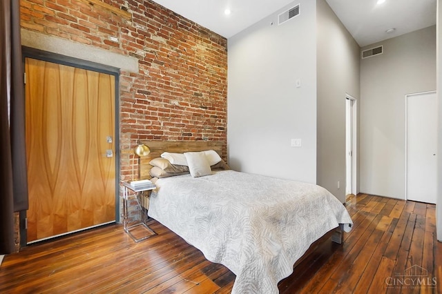 bedroom with a towering ceiling, visible vents, and hardwood / wood-style floors
