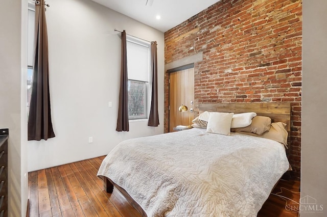 bedroom with brick wall and hardwood / wood-style flooring
