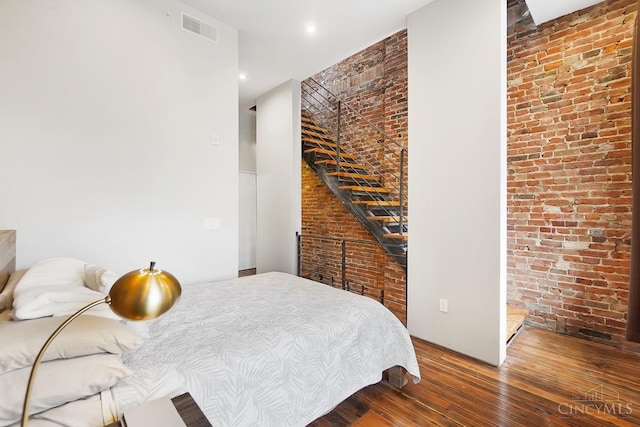 bedroom with brick wall, recessed lighting, visible vents, and hardwood / wood-style flooring