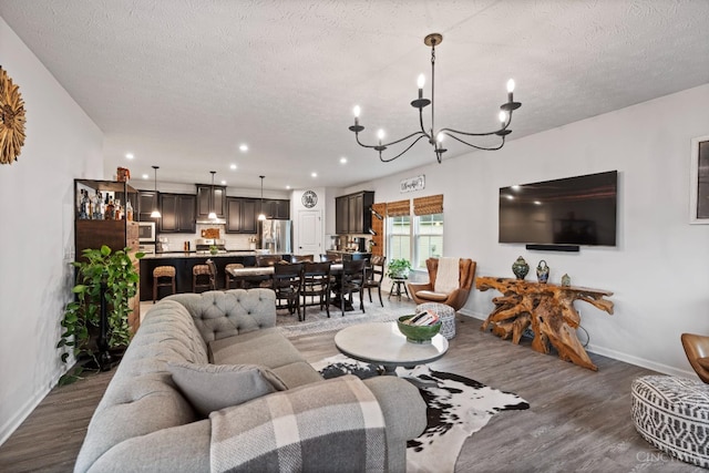 1113 Clover Field Dr, Miami Twp, OH 45140 - living room featuring baseboards, a notable chandelier, wood finished floors, and a textured ceiling
