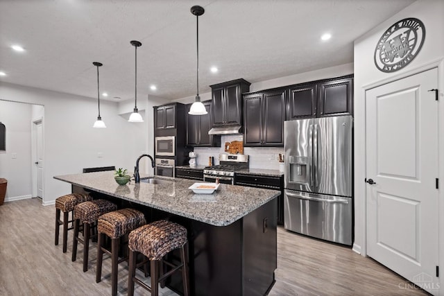 1113 Clover Field Dr, Miami Twp, OH 45140 - kitchen with light wood-type flooring, appliances with stainless steel finishes, a breakfast bar, and a kitchen island with sink
