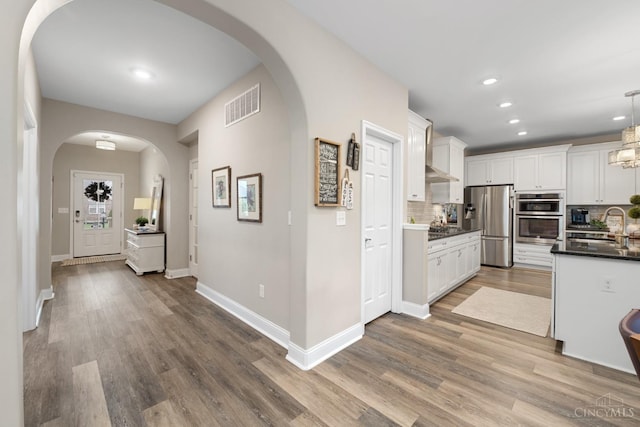 2612 Virgie Ct, Deerfield Twp, OH 45140 - kitchen featuring stainless steel appliances, visible vents, arched walkways, decorative backsplash, and white cabinetry