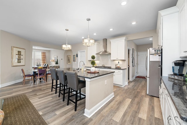 2612 Virgie Ct, Deerfield Twp, OH 45140 - kitchen with light wood finished floors, decorative backsplash, appliances with stainless steel finishes, wall chimney range hood, and a breakfast bar area