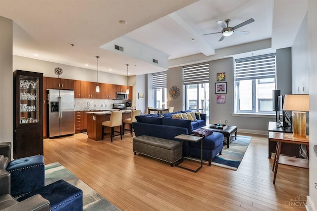 living room with a ceiling fan, light wood finished floors, recessed lighting, and baseboards