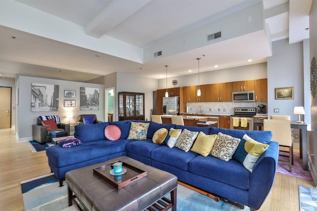 living area with light wood finished floors, recessed lighting, beamed ceiling, and baseboards
