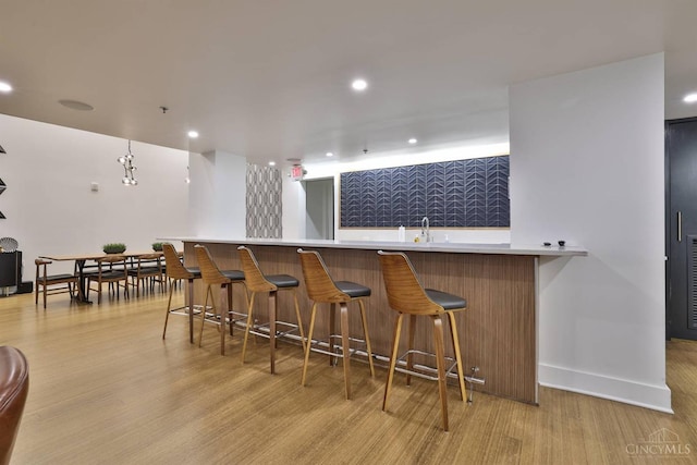 indoor wet bar with light wood finished floors, recessed lighting, and baseboards