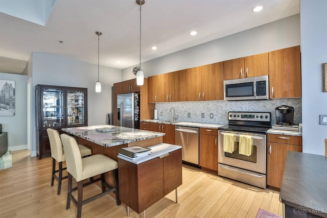 kitchen with stainless steel appliances, brown cabinetry, a center island, decorative backsplash, and recessed lighting