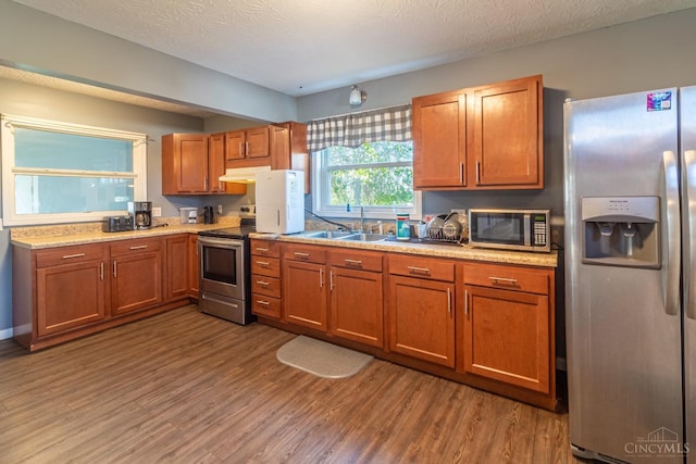 819 E Main St, West Union, OH 45693 - kitchen featuring stainless steel appliances, under cabinet range hood, brown cabinets, and wood finished floors