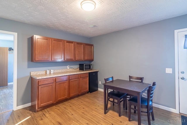 819 E Main St, West Union, OH 45693 - kitchen featuring stainless steel microwave, brown cabinets, and light wood-type flooring