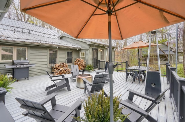 deck with a fire pit, outdoor dining space, and a grill