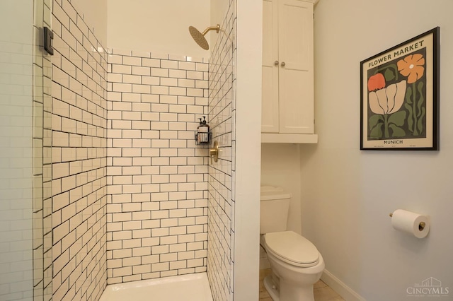 bathroom with toilet, a stall shower, and baseboards