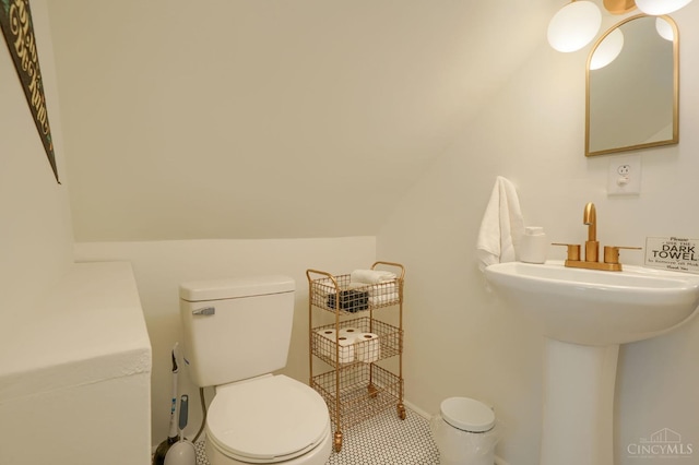 half bathroom with toilet, lofted ceiling, and tile patterned floors